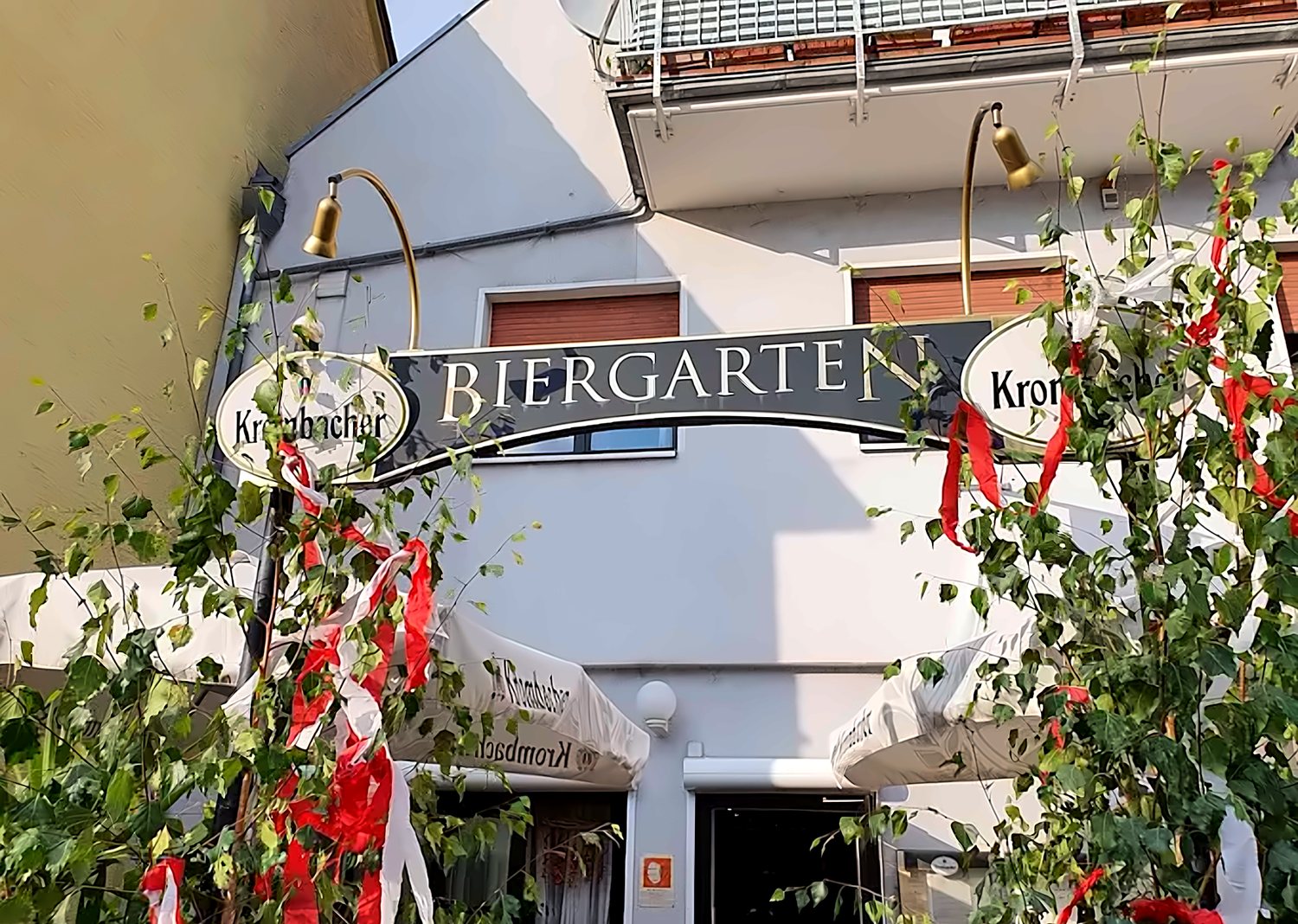 Eingang der Gut Stubb mit Biergarten-Schild und geschmückten Birken